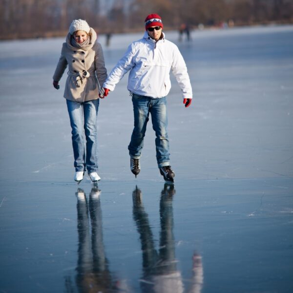 Couple ice skating outdoors on a pond on a lovely sunny winter day
